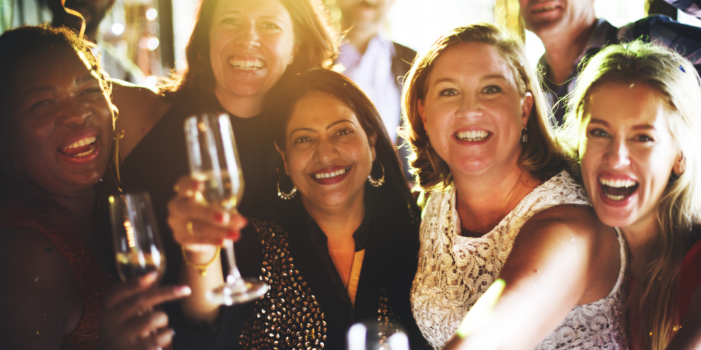 a group of women celebrate holding prosecco