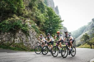Cyclists riding together on a mountainous road, showcasing teamwork amidst a picturesque landscape