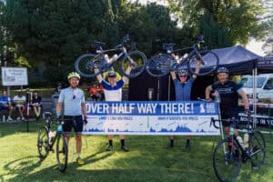 The racers lifting their bikes in celebration at a race, capturing the thrill of competition and teamwork